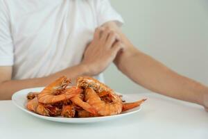 Comida alergias, homens ter reações comichão e vermelhidão depois de comendo camarão, frutos do mar alergia, coceira, irritação na pele, abdominal dor, diarréia, peito aperto, inconsciência, morte, forte evitar alergias foto