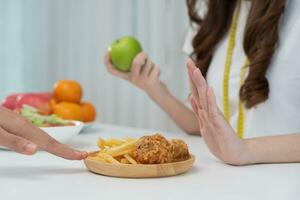 mulheres de corpo magro escolhem durante alimentos saudáveis e junk food, mulheres escolhem maçã verde para dieta. boa comida saudável. perda de peso, equilíbrio, controle, redução de gordura, baixas calorias, rotinas, exercícios. foto