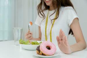 dieta e dieta. corpo feminino magro de beleza confunde rosquinha. mulher em roupas de ginástica atinge meta de perda de peso para uma vida saudável, louca por magreza, cintura fina, nutricionista. foto