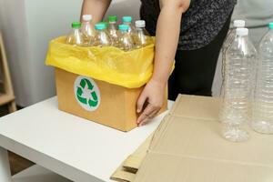 casa reciclar eco verde zero conceito mulher jogando esvaziar plástico garrafa dentro reciclando bin com amarelo lixo bolsas às lar. foto