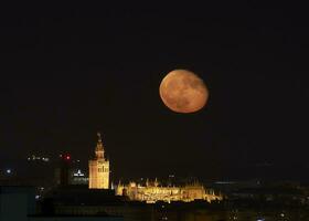 lua sobre a céu do Sevilha com a catedral foto