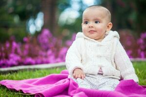 doce seis meses velho bebê menina sentado às a jardim dentro uma lindo ensolarado dia foto