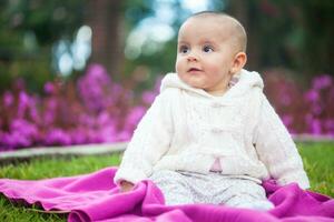 doce seis meses velho bebê menina sentado às a jardim dentro uma lindo ensolarado dia foto