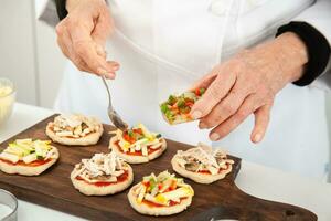 adicionando coberturas para a mini pizzas. adicionando legumes. delicioso caseiro mini pizzas preparação. foto