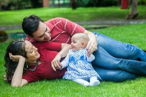 jovem pais tendo Diversão ao ar livre com seus seis meses velho bebê garota. felicidade conceito. família conceito foto