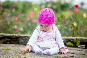 doce seis meses velho bebê menina sentado às a jardim dentro uma lindo ensolarado dia foto