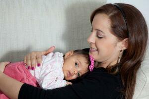 retrato do lindo jovem mãe às casa com dela 1 mês bebê garota. maternidade conceito. família amor conceito. foto