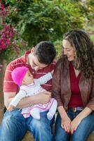 jovem pais tendo Diversão ao ar livre com seus seis meses velho bebê garota. felicidade conceito. família conceito foto