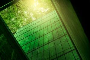edifício ecológico na cidade moderna. edifício de escritórios de vidro sustentável com árvore para reduzir o calor e o dióxido de carbono. prédio de escritórios com ambiente verde. edifício corporativo reduzir o co2. foto