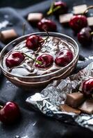 fresco cerejas dentro tigela com chocolate em Sombrio toalha de mesa foto