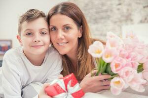 feliz mãe dia conceito. mãe com filho em cama com presente e tulipas foto