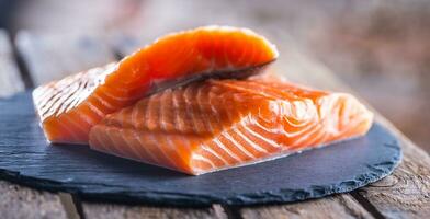 cru salmão filetes em ardósia e de madeira borda foto