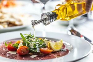 Oliva óleo derramado sobre uma abalou salada dentro uma carpaccio Aperitivo foto