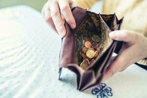 pensionista mulher segurando dentro mãos carteira com euro moedas foto