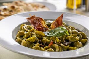 orecchiette pequeno italiano massa com pesto e crocante tiras do bacon foto