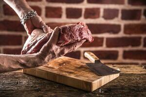 açougueiro homem mãos segurando cru carne bife dentro açougue. foto