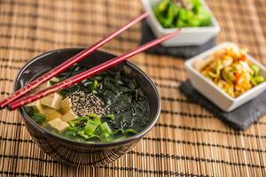 tradicional japonês sopa missô com tofu algas marinhas pauzinhos e jovem cebola foto