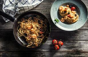 massa espaguete em prato e panela com camarão tomate molho tomates e ervas. italiano ou Mediterrâneo cozinha foto