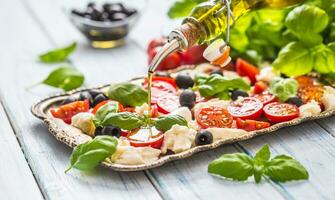 derramando Oliva óleo em caprese salada. saudável italiano ou Mediterrâneo refeição foto