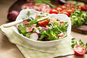 fresco Primavera salada com verde folhas tomates ovo rabanete vermelho cebola jovem ervilhas prosciutto feta queijo e Oliva óleo foto