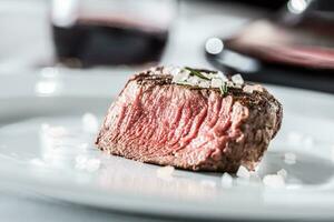 carne filé mignon bife em branco prato e vermelho vinho dentro bar ou restaurante foto