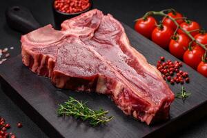 cru fresco suculento carne t-bone bife com sal, especiarias e ervas foto