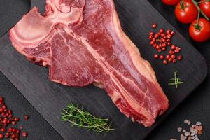 cru fresco suculento carne t-bone bife com sal, especiarias e ervas foto