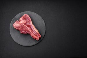 cru fresco suculento carne t-bone bife com sal, especiarias e ervas foto