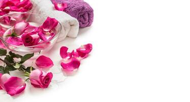 Rosa rosas pétalas dentro tigela com toalhas e puro água sobre branco.. spa e bem estar conceito foto