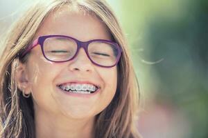 retrato do uma feliz sorridente Adolescência menina com dental suspensórios e óculos foto