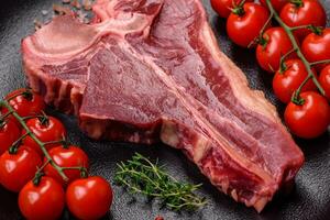 cru fresco suculento carne t-bone bife com sal, especiarias e ervas foto