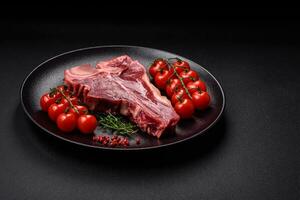 cru fresco suculento carne t-bone bife com sal, especiarias e ervas foto