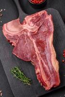 cru fresco suculento carne t-bone bife com sal, especiarias e ervas foto