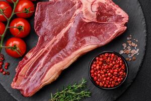 cru fresco suculento carne t-bone bife com sal, especiarias e ervas foto