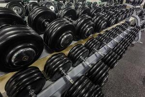 Preto haltere definir. fechar acima muitos emborrachado halteres em prateleira dentro esporte ginástica Centro , peso Treinamento equipamento conceito foto