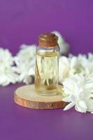 óleos essenciais de eucalipto em uma garrafa de vidro e flores em fundo roxo foto