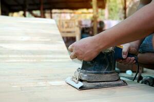 carpinteiros usar uma lixadeira para areia a superfície do a madeira para suave a madeira antes pintura. suave e seletivo foco. foto