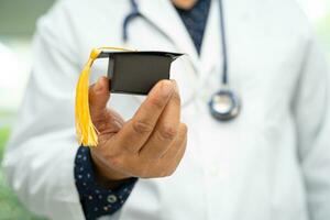 estudo de médico asiático aprende com chapéu de graduação na enfermaria do hospital, conceito de medicina de educação de gênio brilhante inteligente. foto