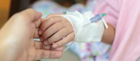 mãe segurando criança mão com salina iv solução dentro hospital foto