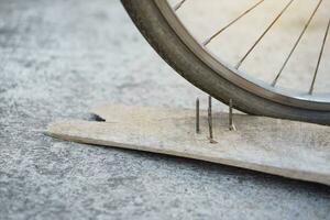 fechar acima unhas em madeira borda e plano bicicleta pneu. conceito, inseguro , dano. estar Cuidado e Veja por aí durante ciclismo em a chão ou risco lugares. acidente pode estar ocorrido. foto