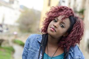 linda mulher negra em meio urbano com cabelo vermelho foto