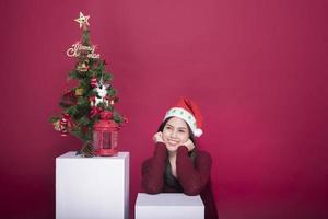 linda garota do papai noel em estúdio em fundo vermelho, conceito de natal foto