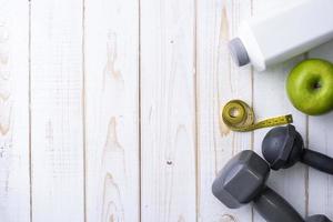 equipamentos de fitness e alimentos saudáveis em fundo branco de madeira foto