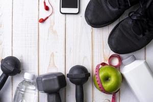 equipamentos de fitness e alimentos saudáveis em fundo branco de madeira foto