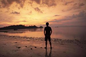 um homem pensativo na praia ao pôr do sol foto