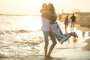 feliz meia idade casal abraçando em a de praia às pôr do sol foto