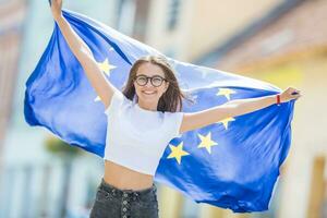 fofa feliz jovem menina com a bandeira do a europeu União dentro a ruas em algum lugar dentro Europa foto