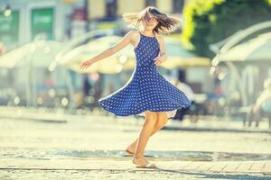 lindo fofa jovem menina dançando em a rua a partir de felicidade.fofo feliz menina dentro verão roupas dançando dentro a Sol. foto