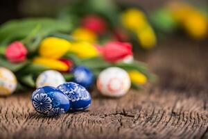 Páscoa. mão fez Páscoa ovos e Primavera tulipas em velho de madeira mesa. foto