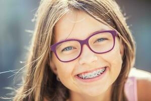 retrato do uma feliz sorridente Adolescência menina com dental suspensórios e óculos foto